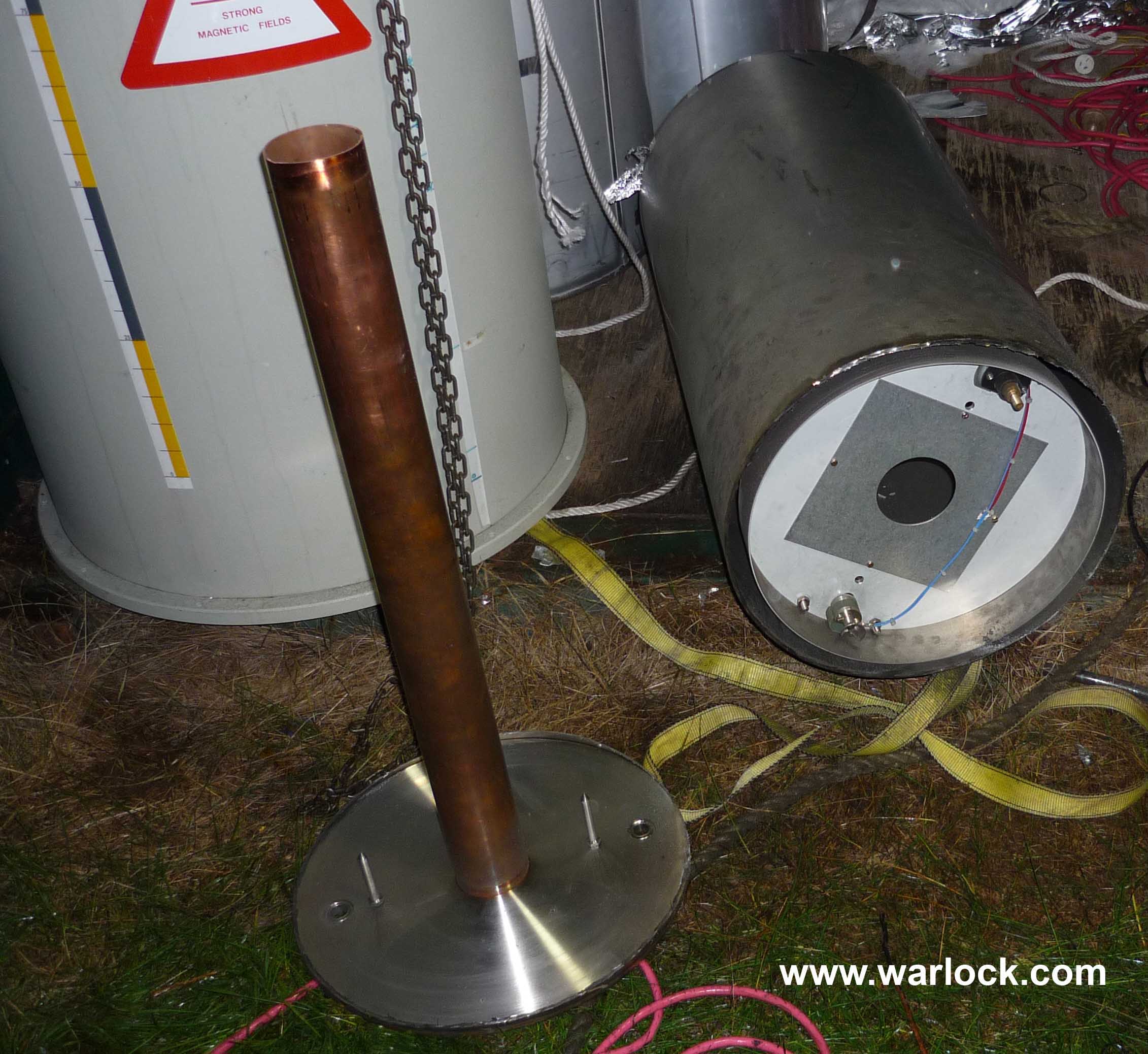 The liquid helium vessel is cut open and the base is removed. A copper tube is connected to the base and extends through the centre of the magnet.